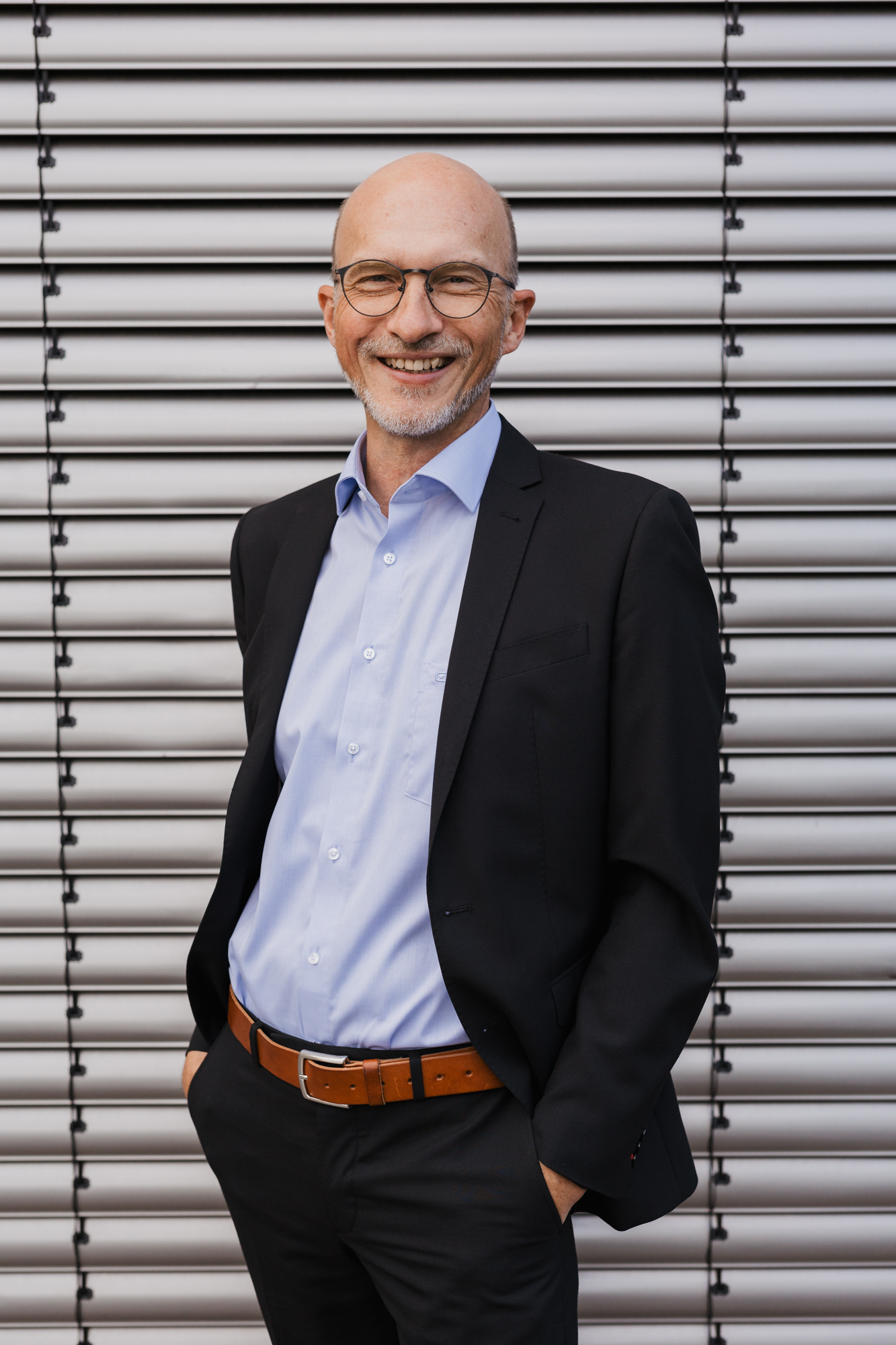 Portraitfoto von Jürgen Schuba, Supervisor in Hameln und Hannover. Er trägt Brille und Sakko und steht vor einem strukturierten Hintergrund.